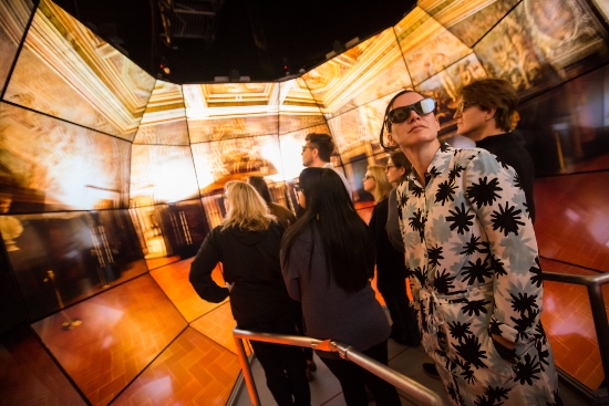 Person with glasses in orange room.