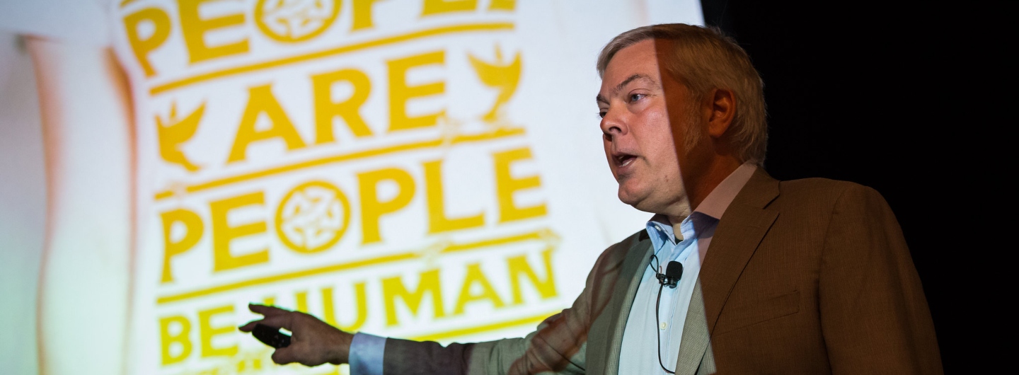 Professor Michael Meyer giving a presentation and pointing while a slide in the background displays a tshirt related to empathy.